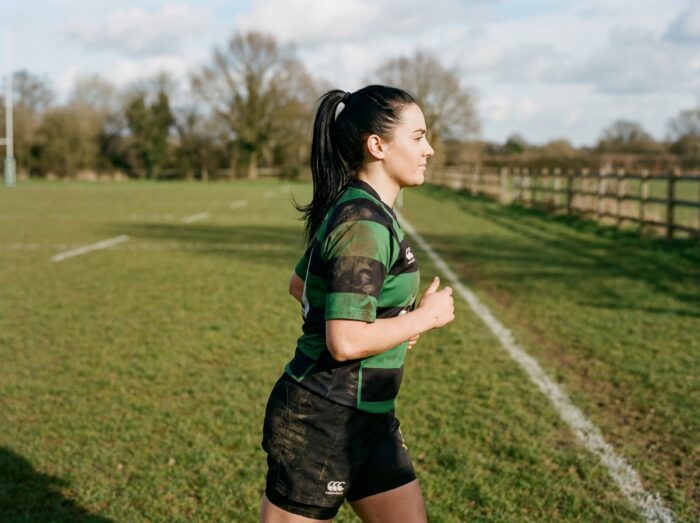 Joueuse de rugby en train de courir lors de son échauffement progressif avant un match de longue durée en club